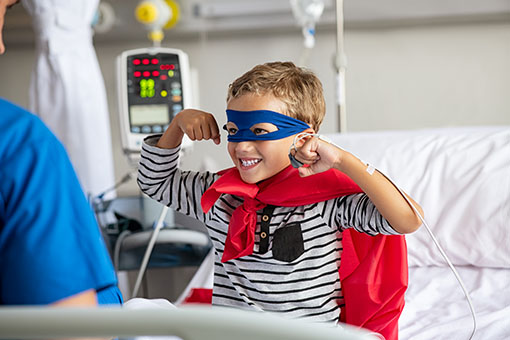 Strong boy in superhero costume at hospital