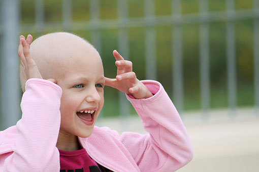 happy child who lost her hair due to chemotherapy to cure cancer